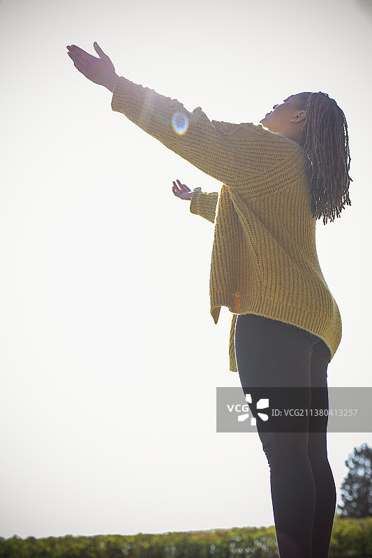 年轻女子沐浴在阳光下，张开双臂图片素材