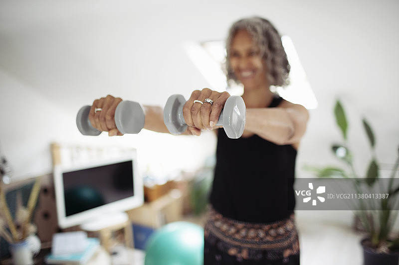 老年妇女在家里用哑铃锻炼图片素材