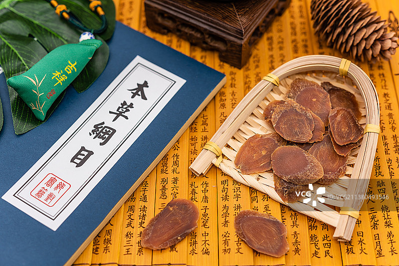 室内棚拍竹简本草纲目背景上的红参草药切片图片素材