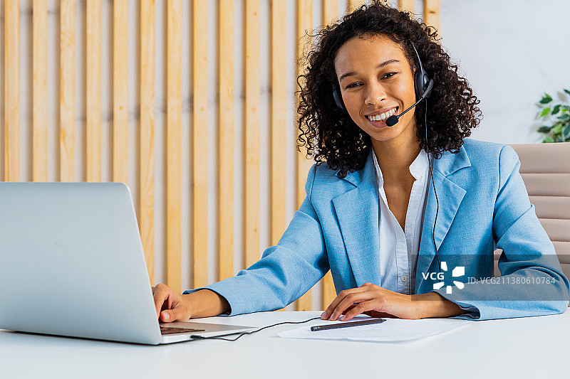 坐在电脑桌前，佩戴麦克风耳机的女商人图片素材