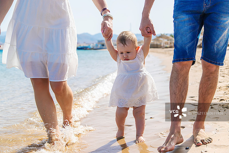 宝宝和父母在海滩上散步（选择性焦点）图片素材