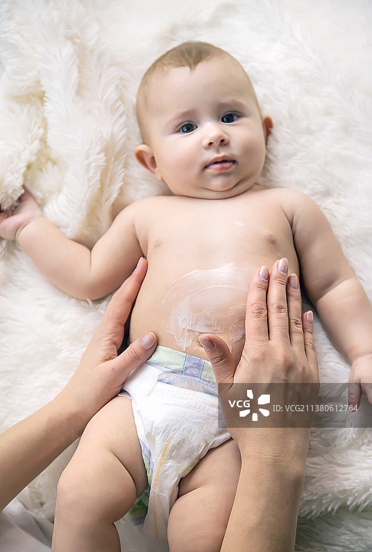 母亲给小宝宝涂润肤霜，局部聚焦图片素材