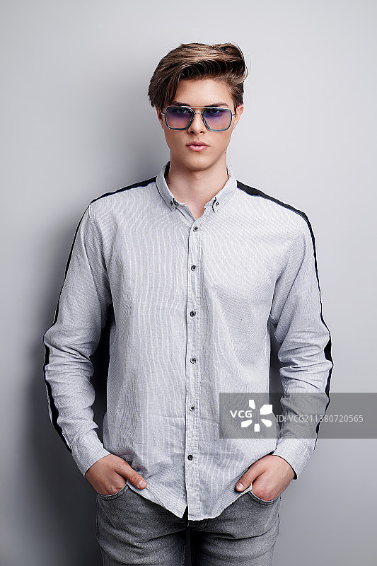 戴着时尚太阳镜，双手插在口袋里的帅气男人图片素材