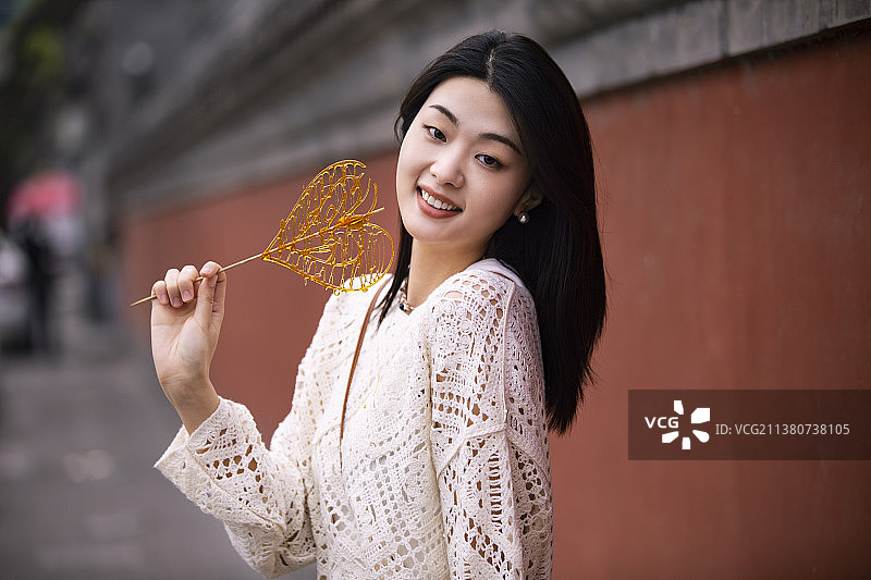 年轻女子在胡同游玩吃棒棒糖图片素材