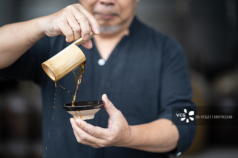 酒厂发酵罐前倒酒品酒的中年男性酿酒师傅图片素材