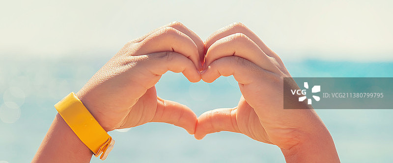 孩子在海边用手比心（选择性焦点）图片素材