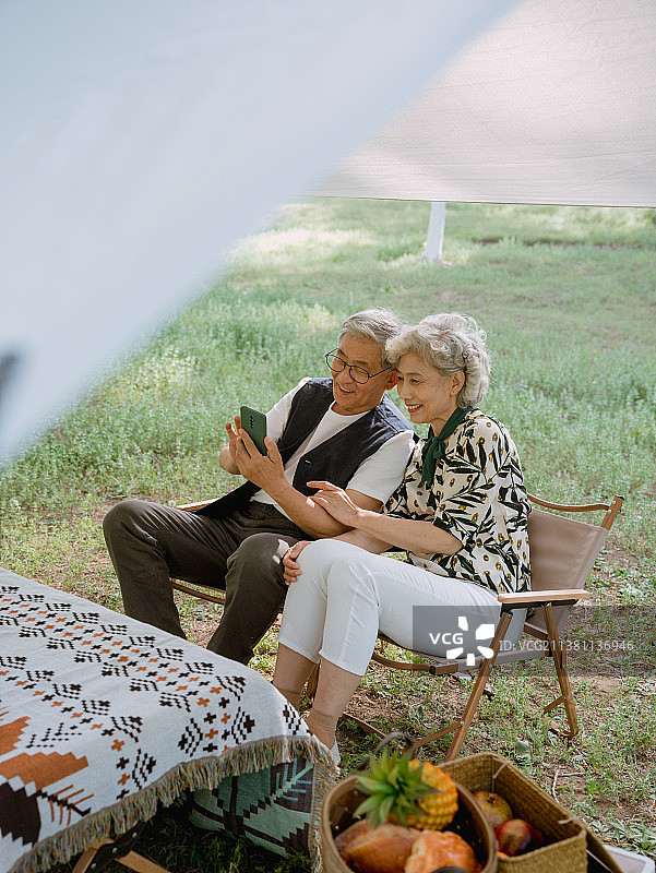 老年夫妇在露营地玩手机图片素材