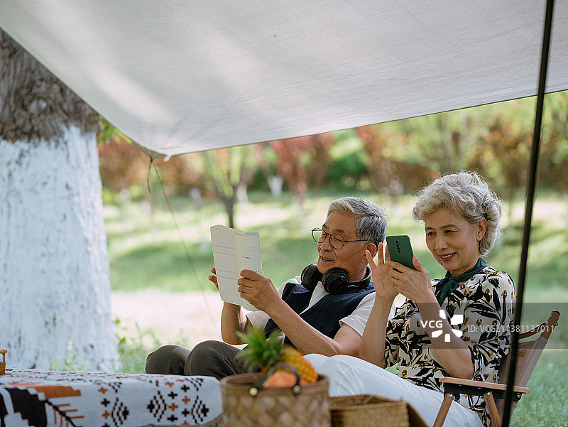 老年夫妇在露营地玩手机图片素材