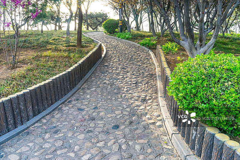 中国自然风光拍摄主题，山东省泰安市龙泽湖公园，绿色的花坛，铺满鹅卵石的铺路石人行步道，户外白昼无人图图片素材
