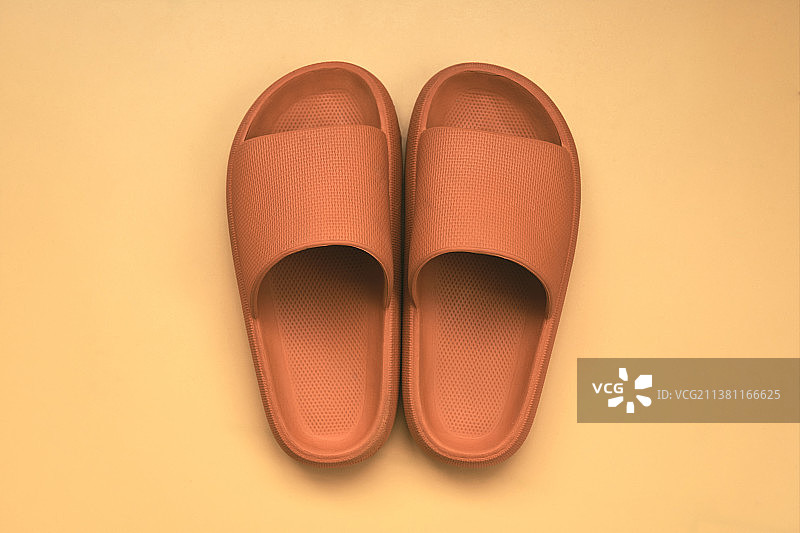 橙色背景上的一双棕色凉拖鞋图片素材