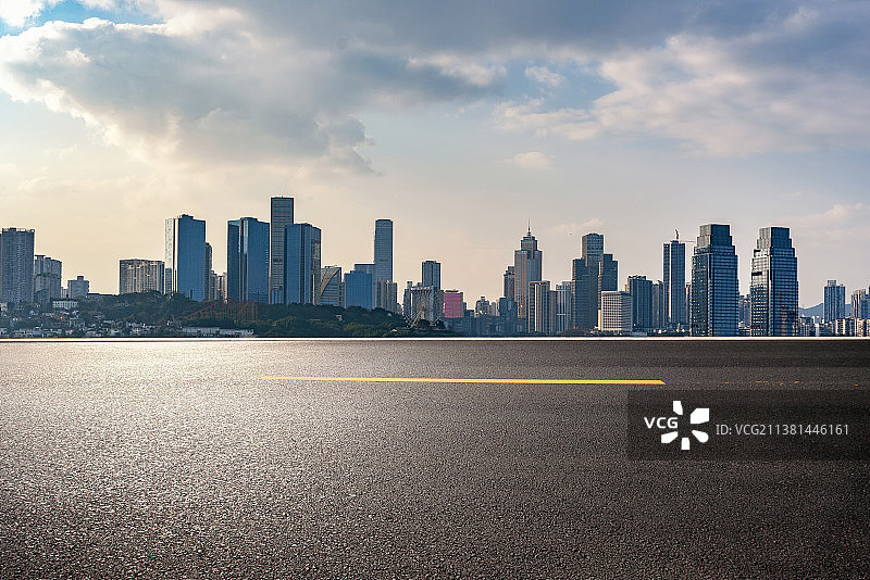 空的沥青道路与日落时的城市天际线图片素材