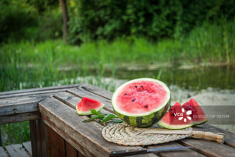 夏季户外水边木桌上切开的冰镇西瓜图片素材