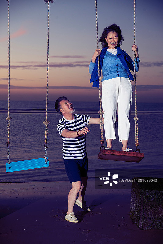 快乐的老年夫妇在海边荡秋千图片素材