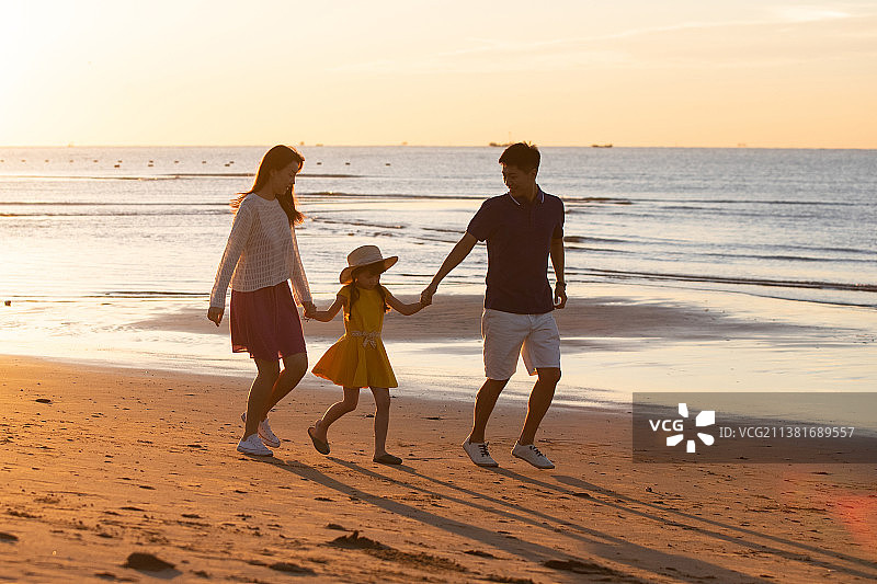 夕阳下一家三口在海边玩耍图片素材