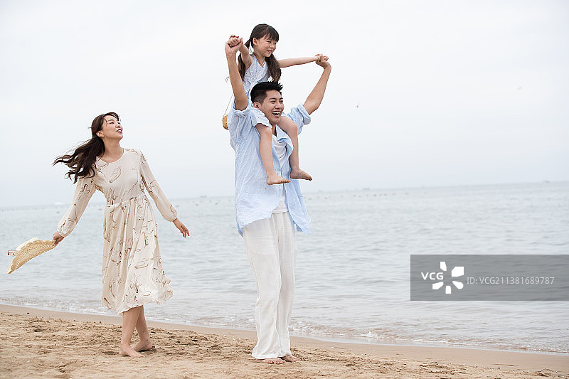 幸福的一家三口在海边玩耍图片素材