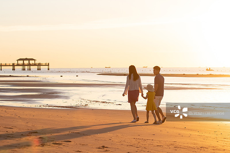 夕阳下一家三口在海边玩耍图片素材