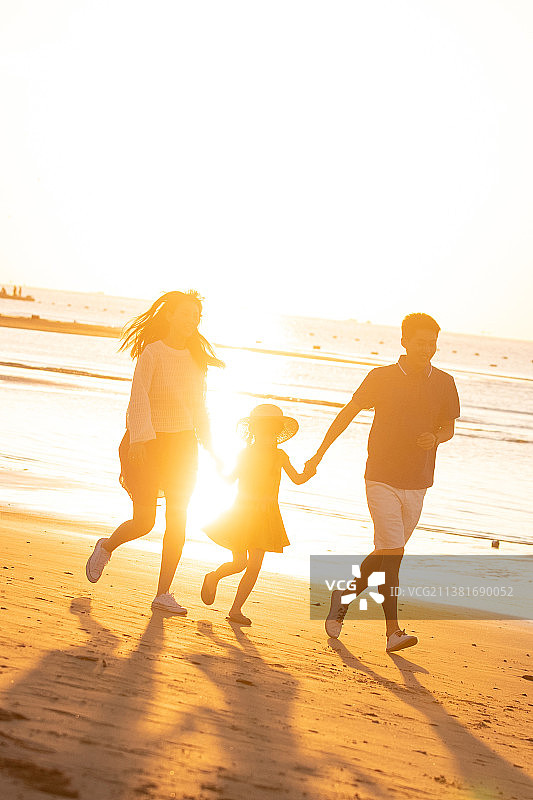 夕阳下一家三口在海边玩耍图片素材