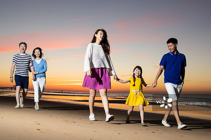 夕阳下在海边散步的幸福家庭图片素材