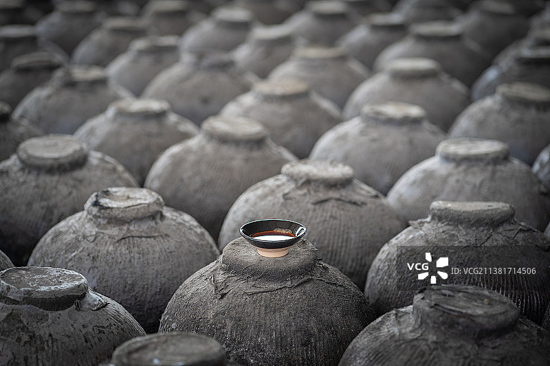 成排落满灰尘的酒坛子上放着一杯红曲米酒图片素材