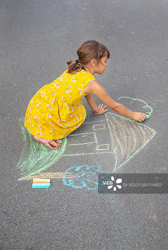 孩子在沥青路面上画房子，选择性聚焦图片素材