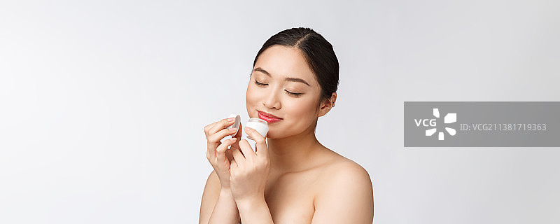 手持化妆品的白色背景美丽年轻女人图片素材