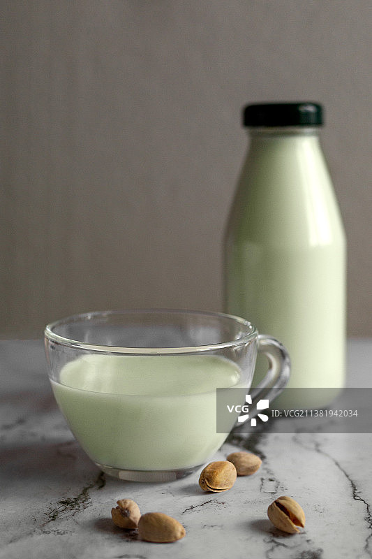 杯子里的开心果奶，旁边有一瓶牛奶和开心果图片素材