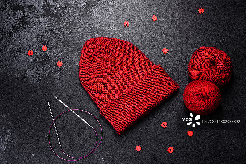 混凝土背景上的红色保暖针织女士帽子图片素材