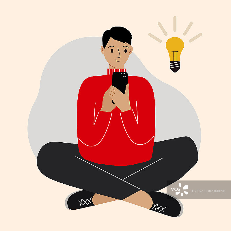 盘腿坐着玩手机的年轻男人图片素材