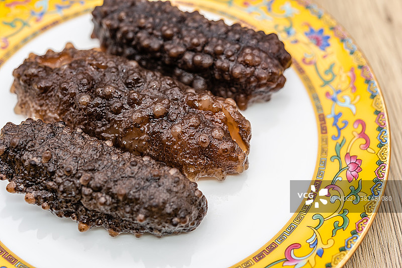 室内棚拍中国宫廷瓷器背景前的一盘海参图片素材