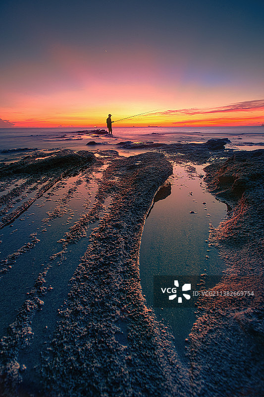 晚霞礁石上的钓客图片素材