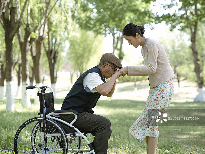 青年女性在公园搀扶着老人图片素材