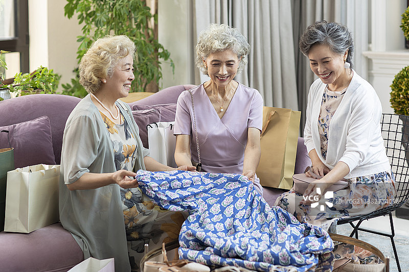 老年女子向朋友展示新买的裙子图片素材