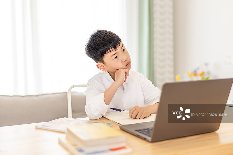 一个亚洲小学生在写作业思考问题图片素材