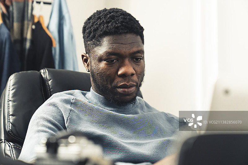 悲伤专注的黑人男子在笔记本电脑上工作图片素材
