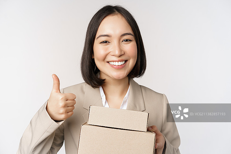 微笑的亚洲女商人展示赞许，拿着快递盒图片素材