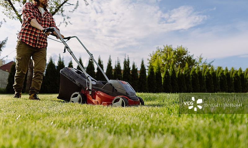 男子在家修剪草坪，园艺工具概念图片素材