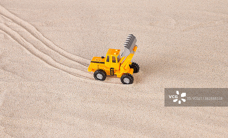 沙滩上的黄色装载机，带有沙子的玩具卡车的高角度视图，摩尔多瓦图片素材