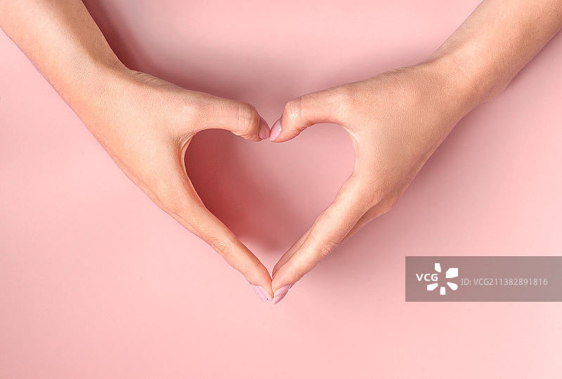 粉色背景上的女性双手比心，爱与友谊图片素材