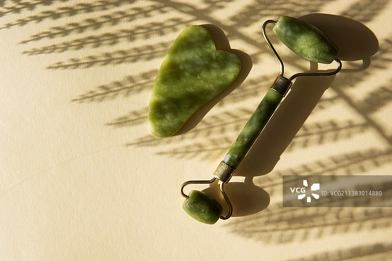 玉石刮痧板和面部滚轮按摩器在软木架上图片素材