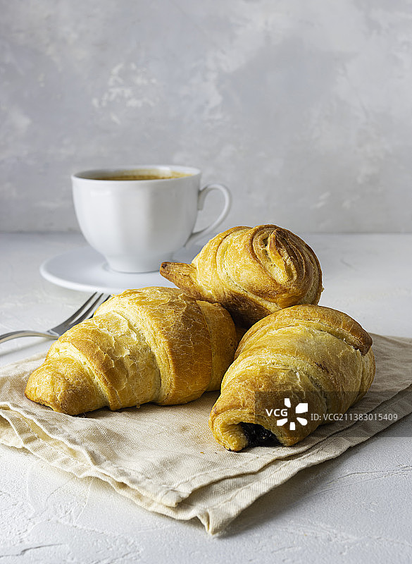 浅色餐巾上的新鲜酥脆巧克力羊角面包图片素材