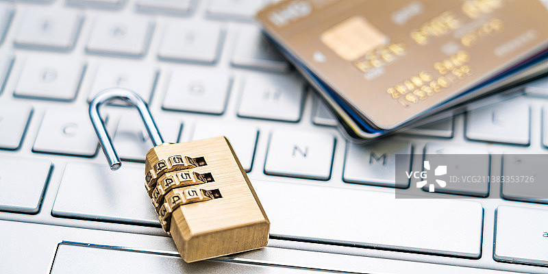 打开的锁子和一叠信用卡放在笔记本键盘上——信用卡盗刷概念图片素材