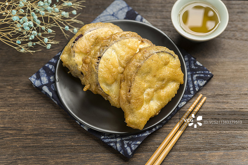 一盘炸茄夹与茶水摆放在木桌面上特写图片素材