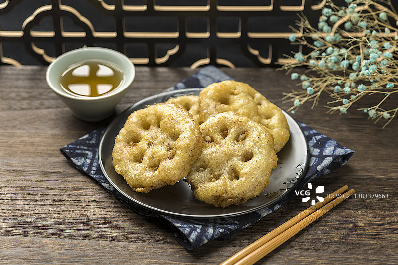 一盘炸藕夹与茶水摆放在木桌面上特写图片素材