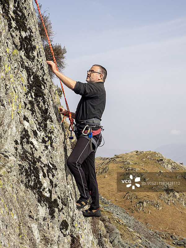 中年登山者在英国康尼斯顿附近的蒂尔伯斯韦特悬崖上开辟新路线图片素材