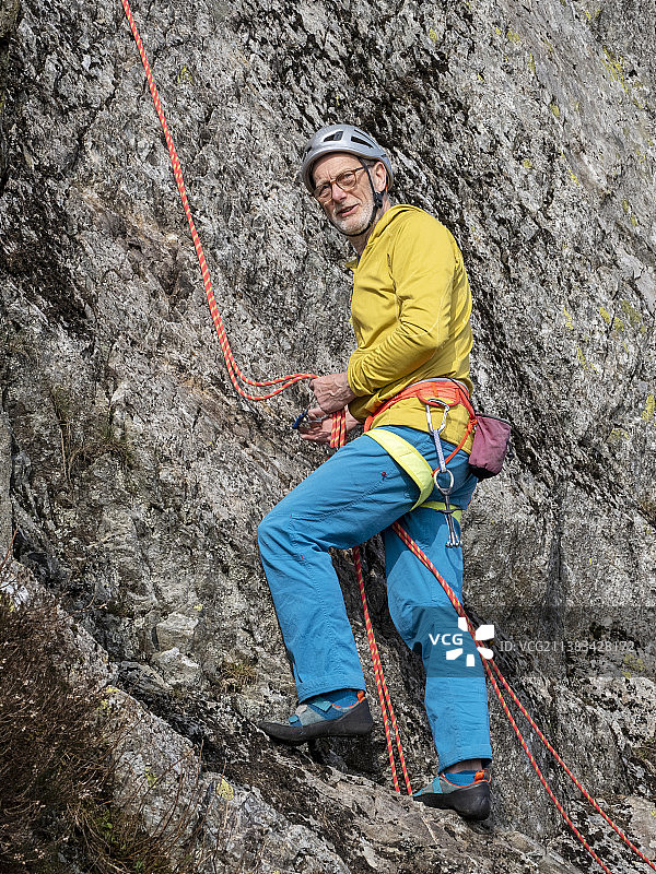 中年登山者在英国康尼斯顿附近的蒂尔伯斯韦特悬崖上开辟新路线图片素材