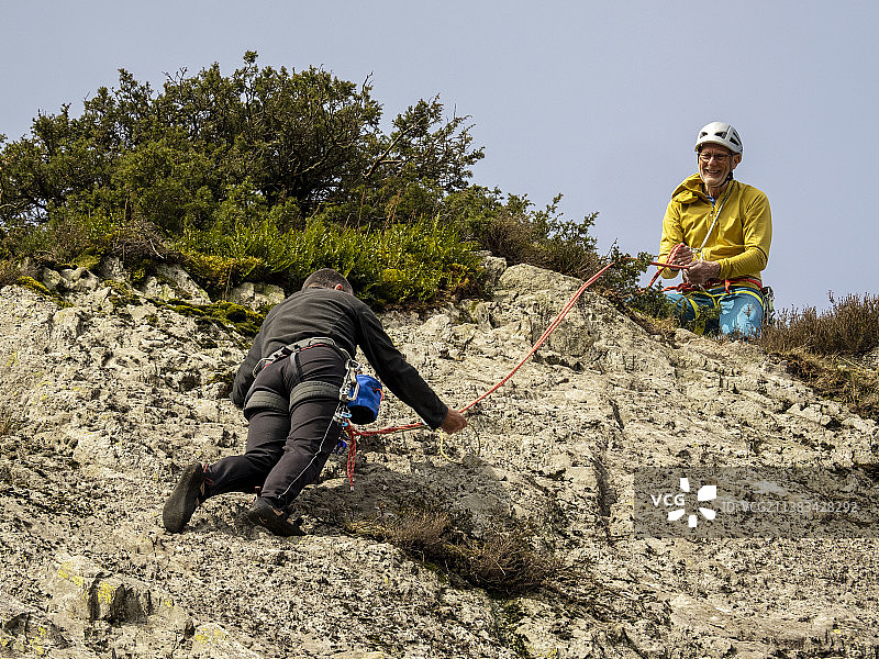 中年登山者在英国康尼斯顿附近的蒂尔伯斯韦特悬崖上开辟新路线图片素材