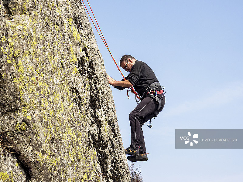 中年登山者在英国康尼斯顿附近的蒂尔伯斯韦特悬崖上开辟新路线图片素材