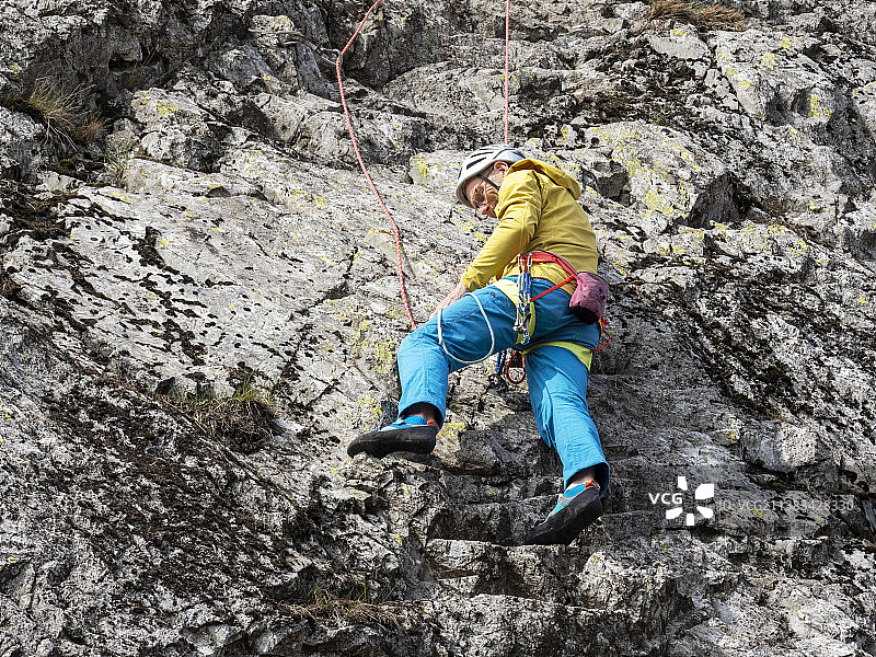 中年登山者在英国康尼斯顿附近的蒂尔伯斯韦特悬崖上开辟新路线图片素材