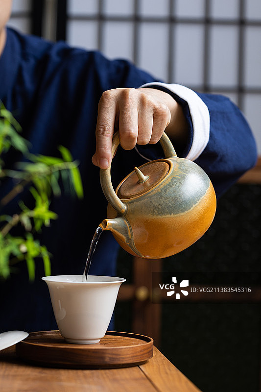 手里拿着提梁壶倒茶水图片素材