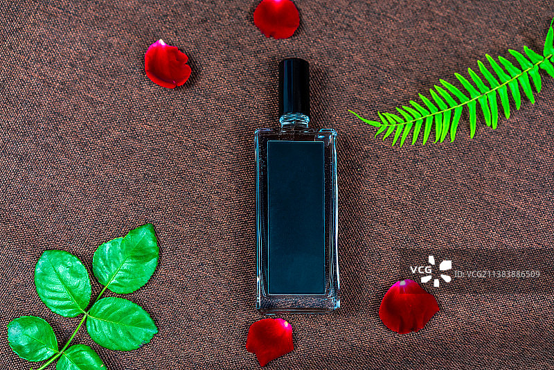红色背景布上的香水瓶和花瓣图片素材